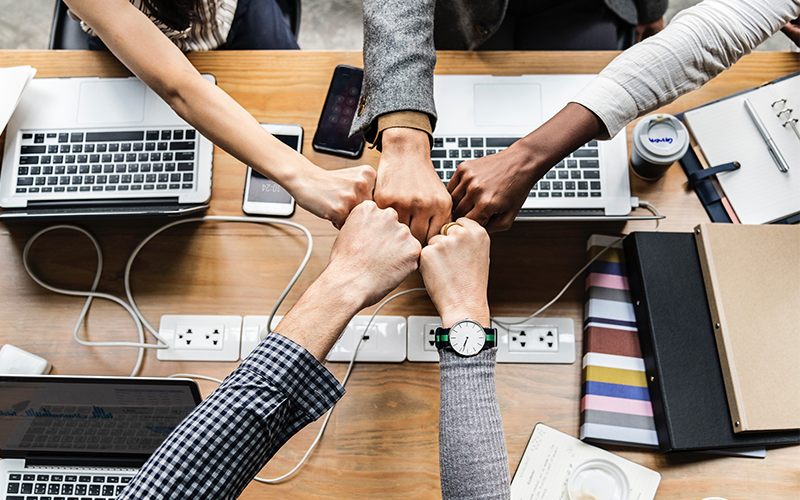 A group of five coworkers fist bumping