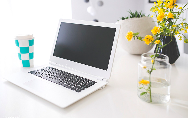 Laptop on a white table with a coffee cup