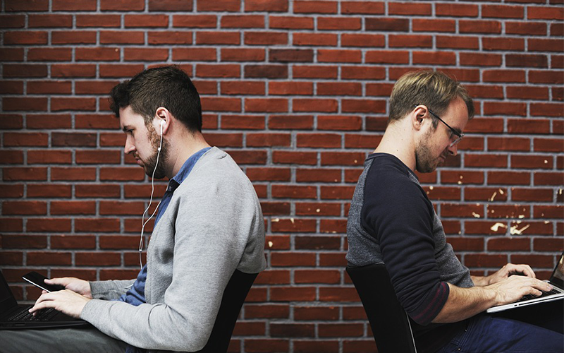 Two men working on their electronic devices