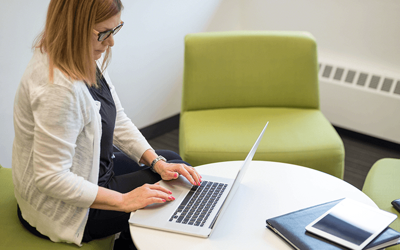 Woman working on her laptop at a white table